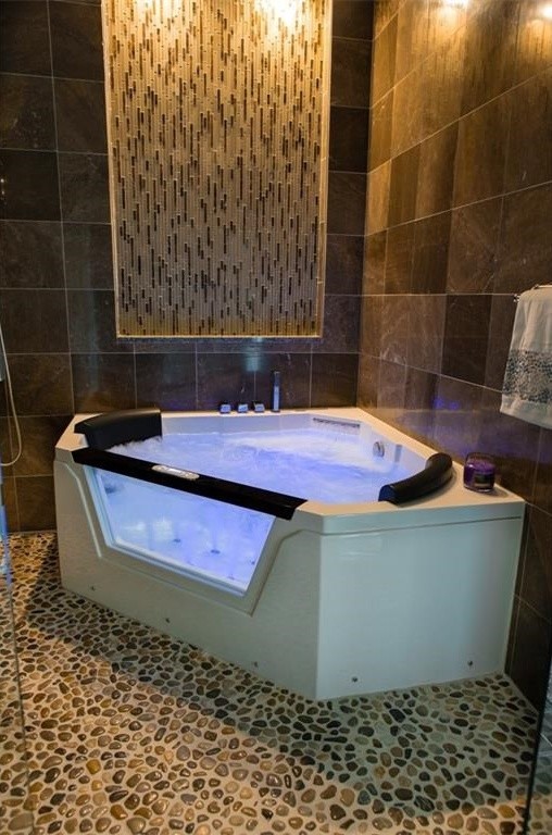 Modern inredning av ett mellanstort en-suite badrum, med möbel-liknande, skåp i mörkt trä, en jacuzzi, en öppen dusch, en vägghängd toalettstol, brun kakel, stenkakel, beige väggar, klinkergolv i keramik, ett integrerad handfat och granitbänkskiva