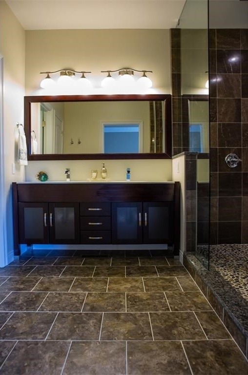 This is an example of a medium sized traditional ensuite bathroom in Indianapolis with freestanding cabinets, dark wood cabinets, a hot tub, a walk-in shower, a wall mounted toilet, brown tiles, stone tiles, beige walls, ceramic flooring, an integrated sink and granite worktops.