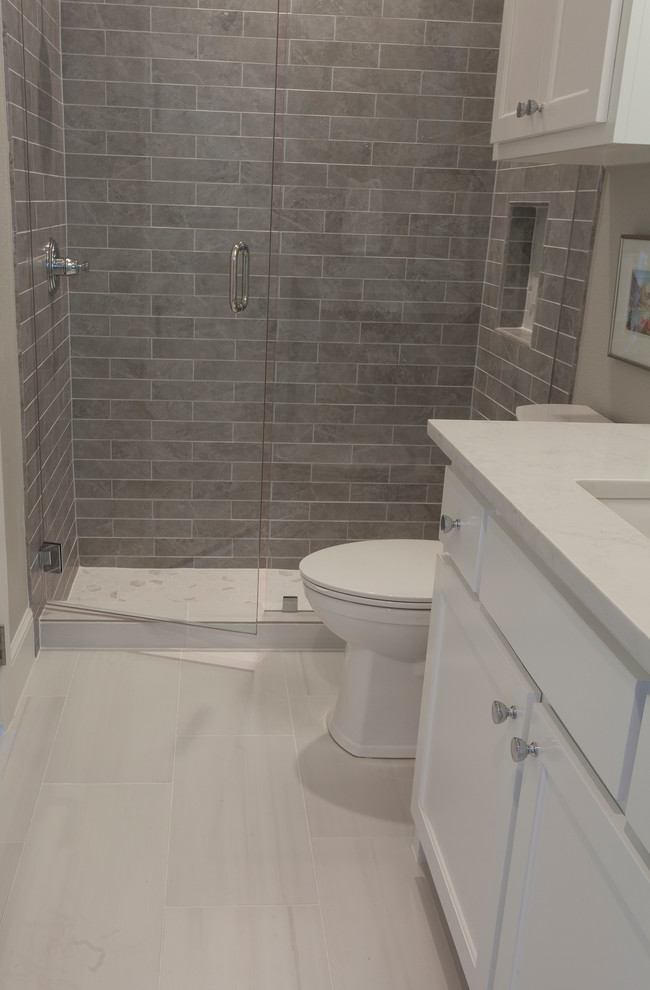 Exemple d'une petite salle de bain chic avec un placard à porte shaker, des portes de placard blanches, une baignoire d'angle, un combiné douche/baignoire, WC à poser, un carrelage gris, des carreaux de céramique, un mur gris, un sol en carrelage de porcelaine, un lavabo encastré, un plan de toilette en quartz modifié, un sol blanc, une cabine de douche avec un rideau et un plan de toilette blanc.