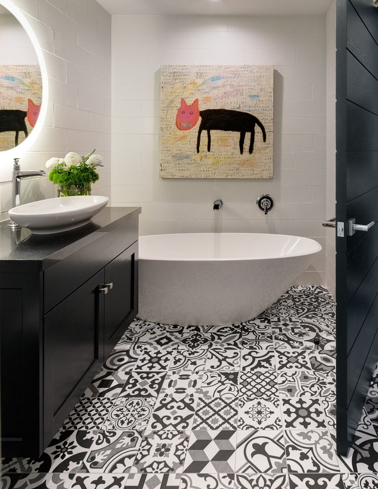 Идея дизайна: ванная комната в стиле фьюжн с фасадами в стиле шейкер, черными фасадами, отдельно стоящей ванной, белой плиткой, душевой кабиной, настольной раковиной, серым полом и черной столешницей