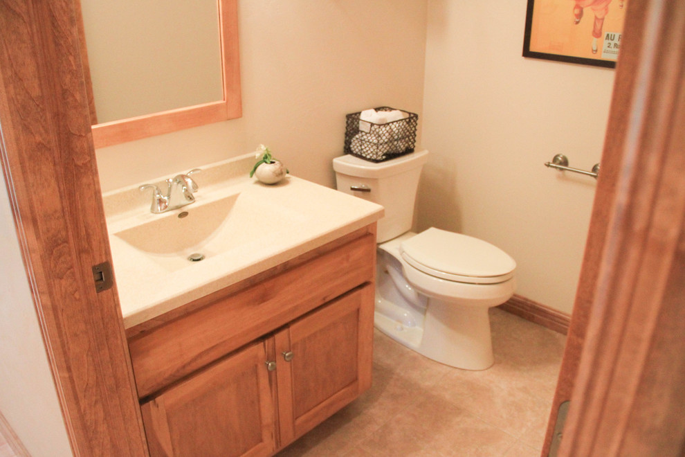 Klassisk inredning av ett litet badrum med dusch, med släta luckor, skåp i ljust trä, ett badkar i en alkov, en dusch/badkar-kombination, en toalettstol med hel cisternkåpa, beige väggar, klinkergolv i keramik, ett integrerad handfat och laminatbänkskiva