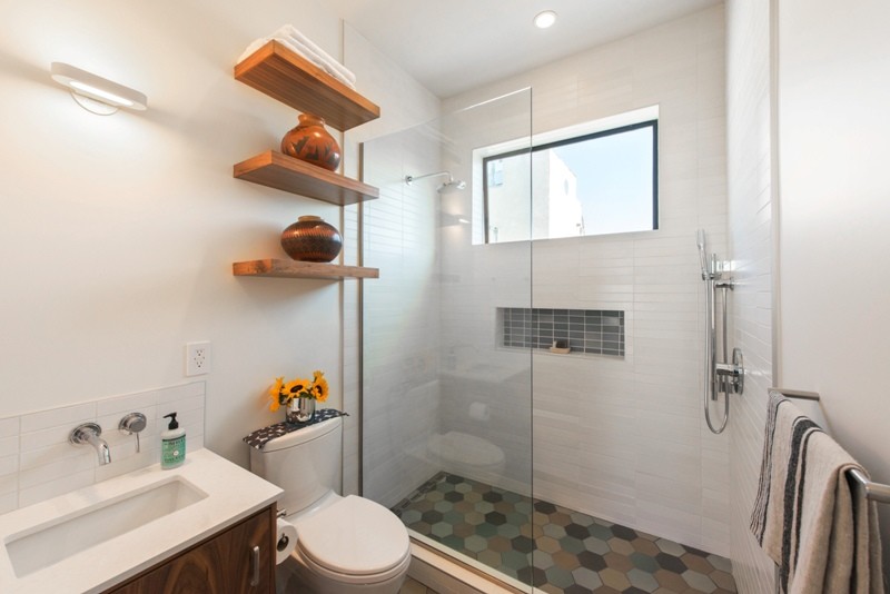 Bild på ett litet funkis badrum med dusch, med släta luckor, skåp i mörkt trä, en dusch i en alkov, en toalettstol med separat cisternkåpa, vit kakel, tunnelbanekakel, vita väggar, klinkergolv i keramik, ett undermonterad handfat och bänkskiva i akrylsten