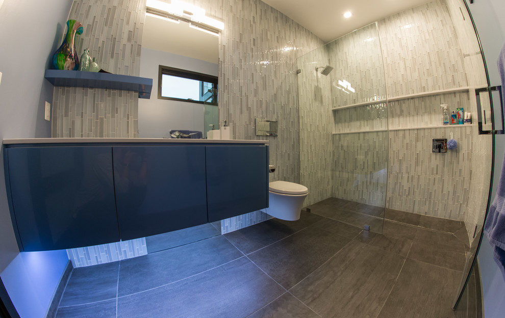 Inspiration för mellanstora moderna badrum med dusch, med släta luckor, grå skåp, en dusch i en alkov, en vägghängd toalettstol, grå kakel, stickkakel, grå väggar, klinkergolv i porslin, ett undermonterad handfat, bänkskiva i kvarts, brunt golv och dusch med gångjärnsdörr