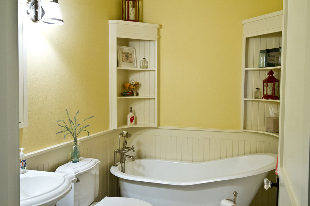 ダラスにある高級な中くらいなトラディショナルスタイルのおしゃれな浴室 (ペデスタルシンク、シェーカースタイル扉のキャビネット、白いキャビネット、置き型浴槽、分離型トイレ、黄色い壁、セラミックタイルの床) の写真
