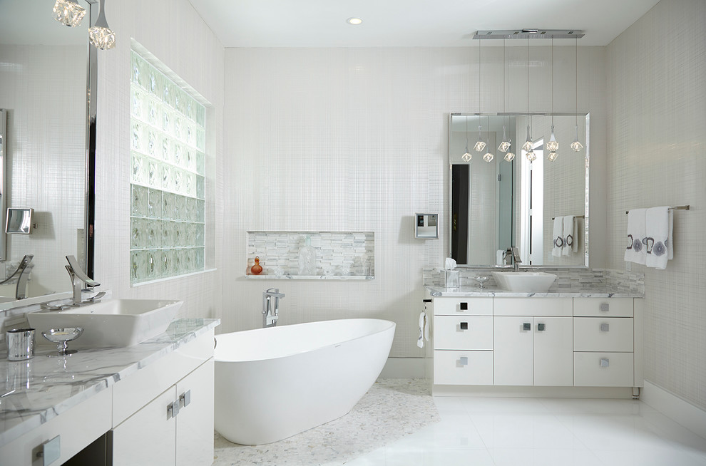 Example of a trendy master white tile freestanding bathtub design in Miami with a vessel sink, flat-panel cabinets, white cabinets and marble countertops