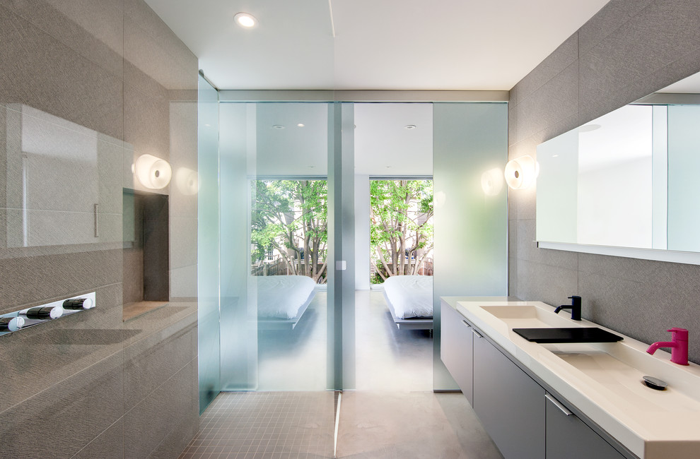 Esempio di una stanza da bagno contemporanea con lavabo integrato, ante lisce e piastrelle grigie