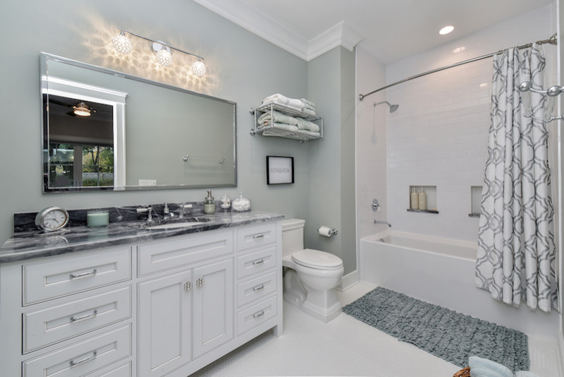 Inredning av ett amerikanskt stort badrum med dusch, med luckor med profilerade fronter, ett platsbyggt badkar, en dusch/badkar-kombination, vit kakel, gröna väggar, klinkergolv i keramik, ett undermonterad handfat, bänkskiva i kvarts, vita skåp och en toalettstol med hel cisternkåpa