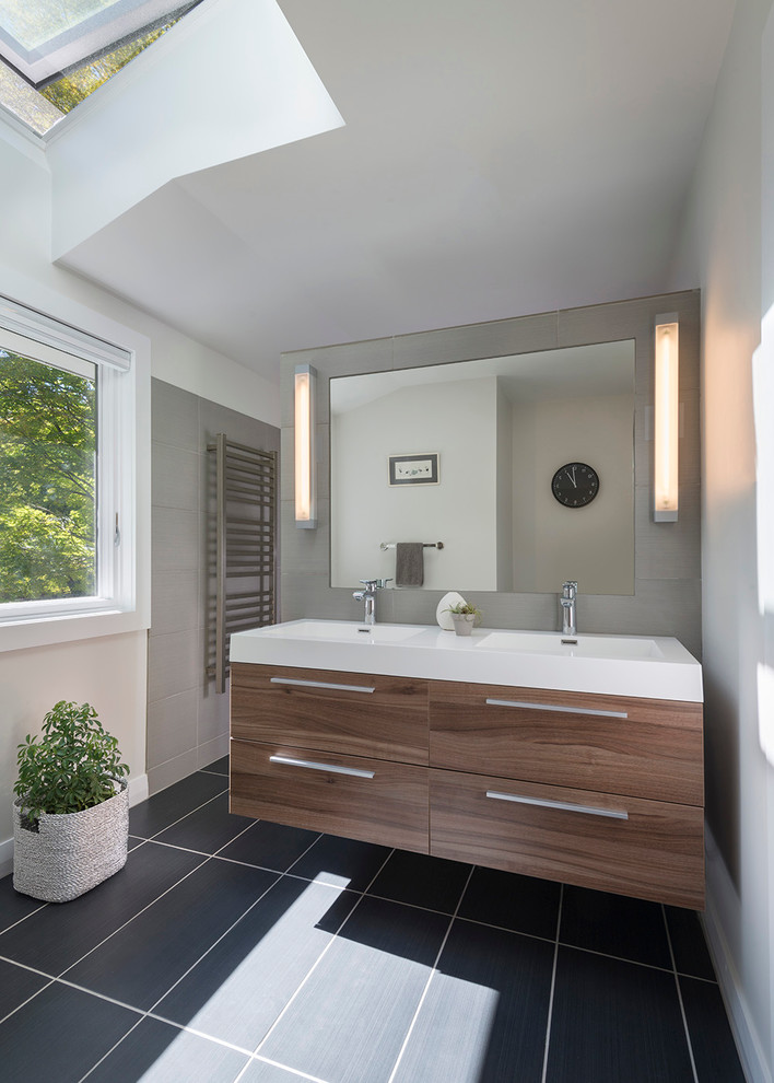 Exemple d'une salle de bain principale rétro en bois brun avec un placard à porte plane, WC séparés, un carrelage gris, des carreaux de céramique, un mur blanc, un sol en carrelage de céramique, un lavabo intégré et un plan de toilette en surface solide.