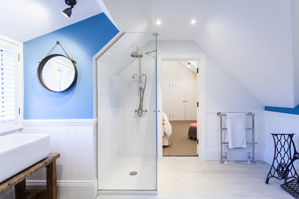Foto på ett stort maritimt badrum, med ett fristående handfat, skåp i slitet trä, en hörndusch, vit kakel, tunnelbanekakel, blå väggar och klinkergolv i keramik