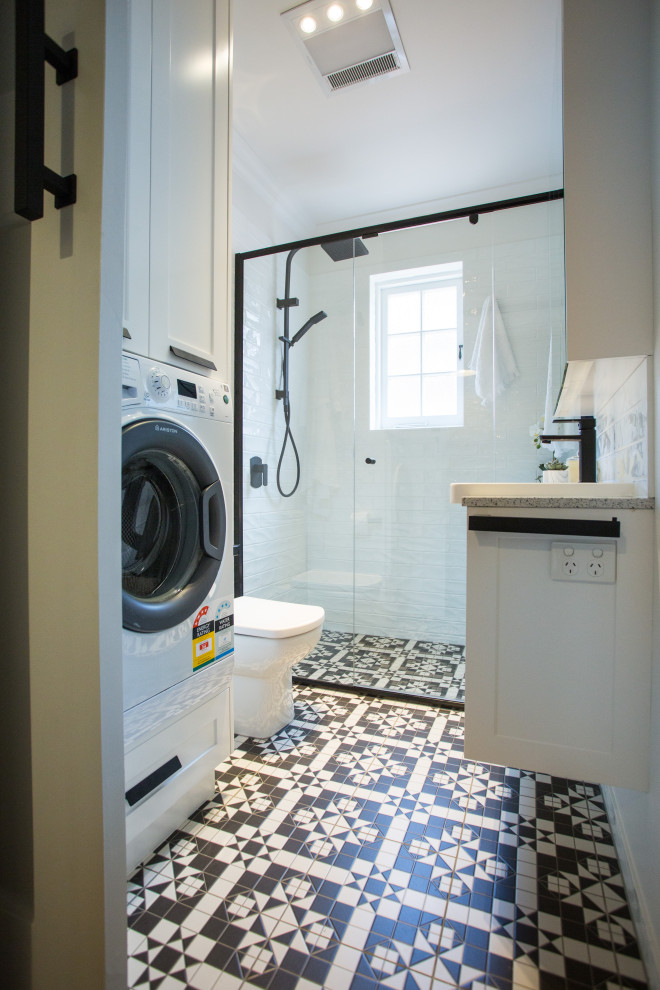Mid-sized trendy master white tile and ceramic tile cement tile floor, black floor and single-sink bathroom photo in Brisbane with white cabinets, a one-piece toilet, white walls, a drop-in sink, quartz countertops, a hinged shower door, white countertops, shaker cabinets and a built-in vanity