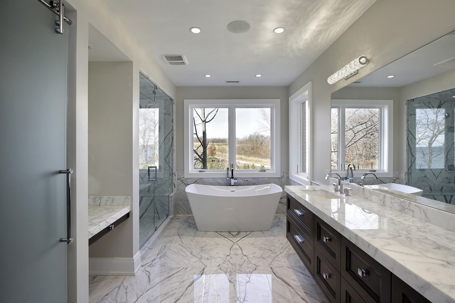 Large traditional ensuite bathroom in Chicago with recessed-panel cabinets, dark wood cabinets, a freestanding bath, an alcove shower, white tiles, marble tiles, grey walls, marble flooring, a submerged sink, marble worktops, white floors and a hinged door.
