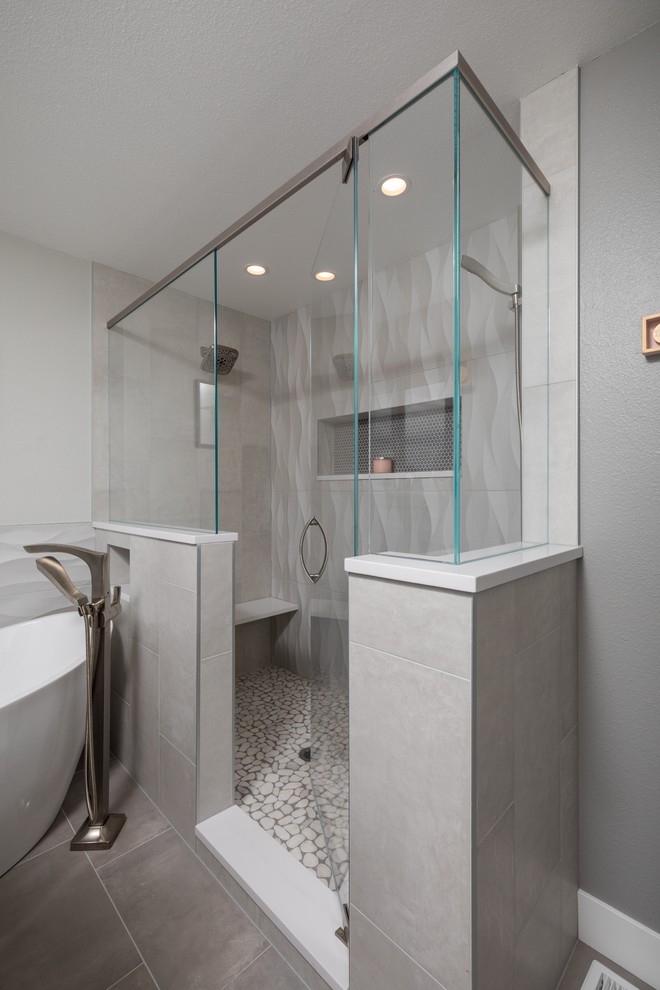 Inredning av ett lantligt mellanstort vit vitt en-suite badrum, med släta luckor, grå skåp, ett fristående badkar, en hörndusch, grå kakel, porslinskakel, grå väggar, klinkergolv i porslin, ett undermonterad handfat, bänkskiva i akrylsten, grått golv och dusch med gångjärnsdörr