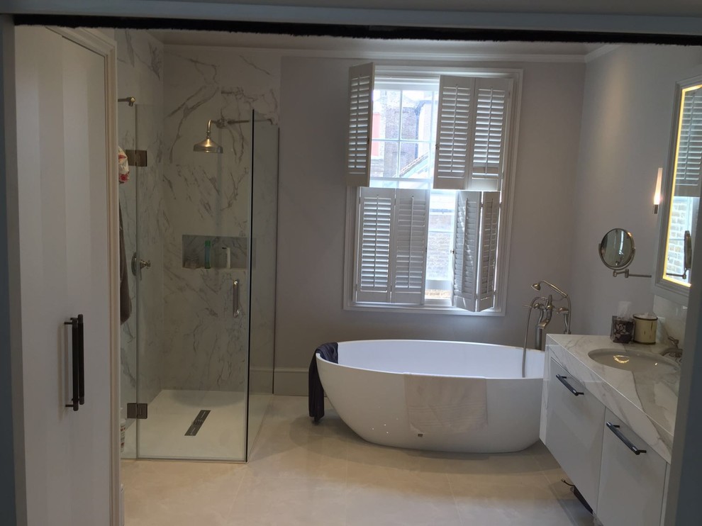 Bild på ett stort funkis badrum, med luckor med infälld panel, grå skåp, ett fristående badkar, en hörndusch, en vägghängd toalettstol, beige kakel, cementkakel, grå väggar, klinkergolv i keramik, ett nedsänkt handfat och marmorbänkskiva