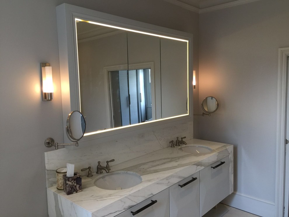 This is an example of a large modern family bathroom in London with recessed-panel cabinets, grey cabinets, a freestanding bath, a corner shower, a wall mounted toilet, beige tiles, cement tiles, grey walls, ceramic flooring, a built-in sink and marble worktops.