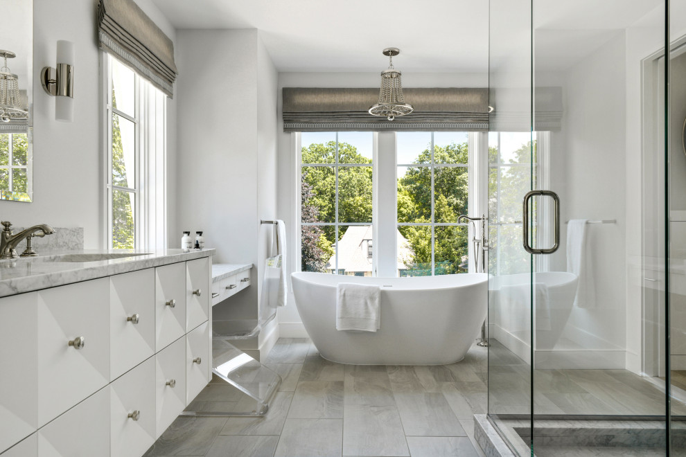 This is an example of a large traditional ensuite bathroom in Minneapolis with white cabinets, a freestanding bath, a corner shower, white walls, light hardwood flooring, a submerged sink, marble worktops, a hinged door, white worktops, an enclosed toilet, double sinks and a floating vanity unit.