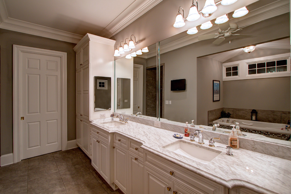 Photo of a large traditional ensuite bathroom in Charleston with recessed-panel cabinets, white cabinets, an alcove bath, grey walls, porcelain flooring, a submerged sink and engineered stone worktops.