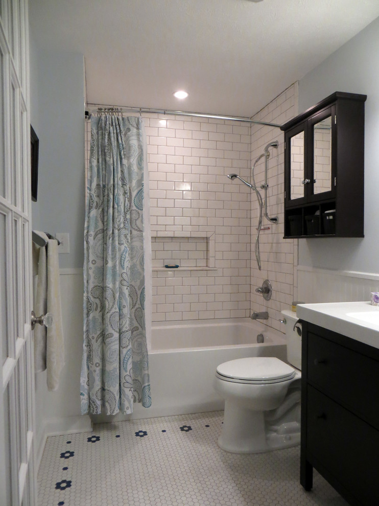 Mittelgroßes Klassisches Badezimmer mit integriertem Waschbecken, verzierten Schränken, dunklen Holzschränken, Mineralwerkstoff-Waschtisch, Einbaubadewanne, Duschbadewanne, Toilette mit Aufsatzspülkasten, weißen Fliesen, Metrofliesen, blauer Wandfarbe und Mosaik-Bodenfliesen in Wichita