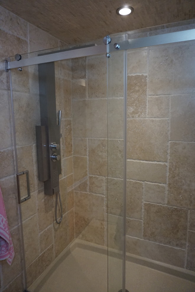 Exemple d'une salle de bain moderne de taille moyenne avec WC à poser, un carrelage beige, du carrelage en travertin, un mur beige, un sol en travertin, un lavabo de ferme, un sol beige et une cabine de douche à porte coulissante.