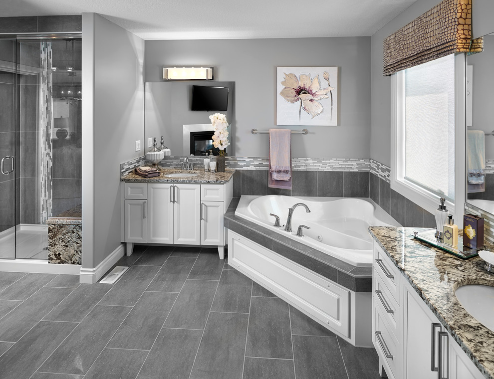 Пример оригинального дизайна: ванная комната в стиле неоклассика (современная классика) с врезной раковиной, угловой ванной, душем в нише, серой плиткой, керамической плиткой, фасадами с утопленной филенкой и белыми фасадами