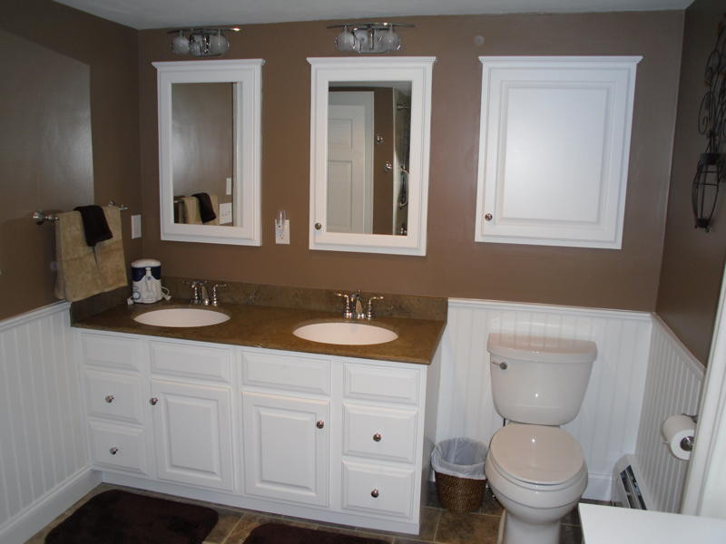 Bild på ett mellanstort vintage badrum med dusch, med luckor med upphöjd panel, vita skåp, ett badkar i en alkov, en dusch/badkar-kombination, en toalettstol med separat cisternkåpa, beige kakel, stenkakel, bruna väggar, klinkergolv i porslin, ett undermonterad handfat och bänkskiva i akrylsten