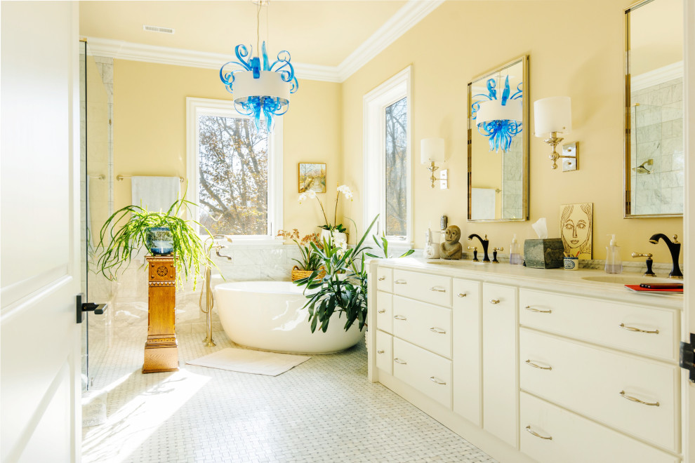 Пример оригинального дизайна: большая главная ванная комната в современном стиле с плоскими фасадами, белыми фасадами, отдельно стоящей ванной, угловым душем, белой плиткой, мраморной плиткой, мраморным полом, врезной раковиной, мраморной столешницей, белым полом, душем с распашными дверями, белой столешницей, тумбой под две раковины, встроенной тумбой и желтыми стенами