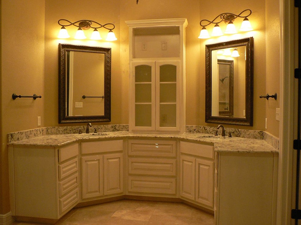 Idée de décoration pour une salle de bain tradition avec des portes de placard blanches, un mur beige, un sol en travertin, un lavabo encastré et un plan de toilette en granite.