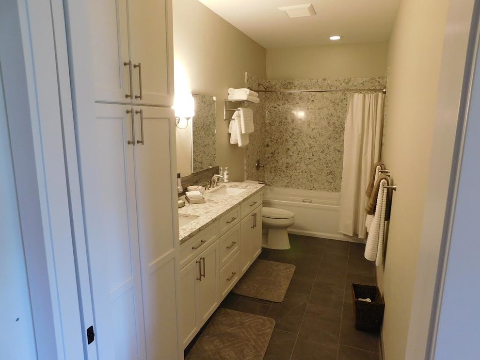 Bild på ett mellanstort lantligt badrum med dusch, med skåp i shakerstil, vita skåp, ett badkar i en alkov, en dusch/badkar-kombination, en toalettstol med separat cisternkåpa, vit kakel, stenhäll, beige väggar, klinkergolv i porslin, ett undermonterad handfat, granitbänkskiva, grått golv och dusch med duschdraperi
