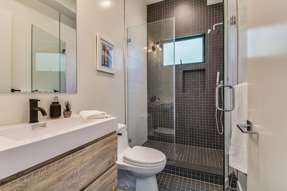 Design ideas for a large nautical shower room bathroom in Los Angeles with flat-panel cabinets, light wood cabinets, white tiles, black tiles, ceramic tiles, white walls, ceramic flooring, granite worktops, black floors, a hinged door, white worktops, an alcove shower, a one-piece toilet and a console sink.