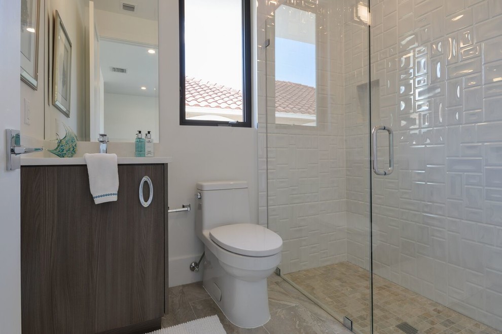 Contemporary shower room bathroom in Miami with flat-panel cabinets, grey cabinets, a built-in shower, a one-piece toilet, white tiles, porcelain tiles, white walls, ceramic flooring, a submerged sink, solid surface worktops, beige floors and a hinged door.