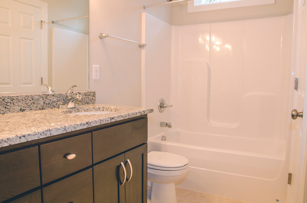 Small traditional family bathroom in Richmond with shaker cabinets, black cabinets, an alcove bath, a shower/bath combination, a two-piece toilet, beige walls, laminate floors, a submerged sink and granite worktops.