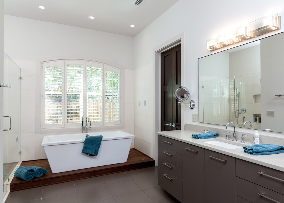 This is an example of a medium sized contemporary ensuite bathroom in Atlanta with a submerged sink, flat-panel cabinets, grey cabinets, quartz worktops, a freestanding bath, a corner shower, a one-piece toilet, beige tiles, ceramic tiles, white walls and porcelain flooring.
