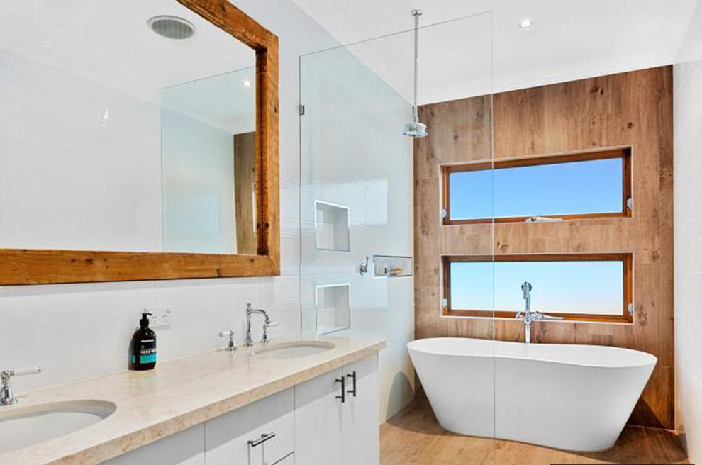 Idéer för ett mellanstort maritimt en-suite badrum, med släta luckor, vita skåp, ett fristående badkar, en öppen dusch, glaskakel, vita väggar, mellanmörkt trägolv, marmorbänkskiva, brunt golv och med dusch som är öppen