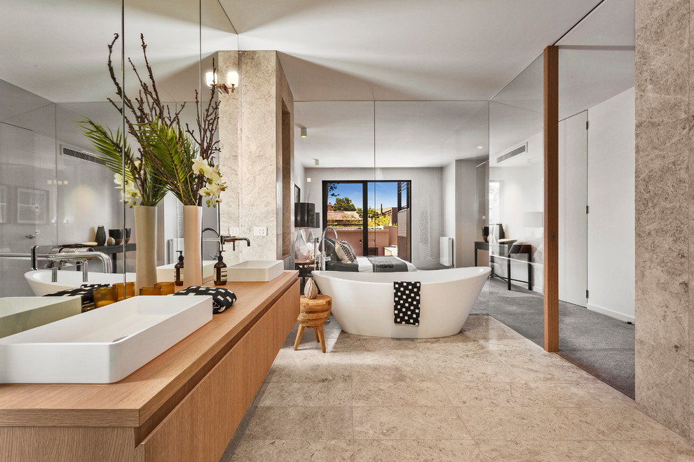 Пример оригинального дизайна: большая главная ванная комната в современном стиле с светлыми деревянными фасадами, отдельно стоящей ванной, столешницей из дерева и коричневой столешницей