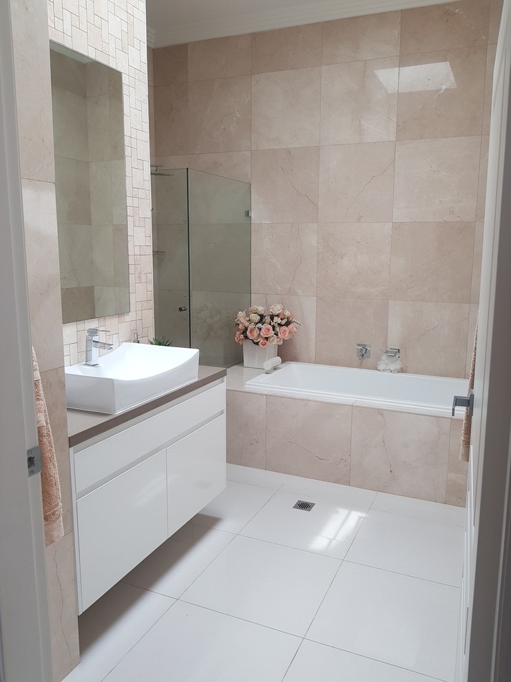 Photo of a medium sized contemporary ensuite bathroom in Sydney with freestanding cabinets, white cabinets, a built-in bath, pink tiles, ceramic tiles, pink walls, ceramic flooring, a built-in sink, laminate worktops and beige worktops.