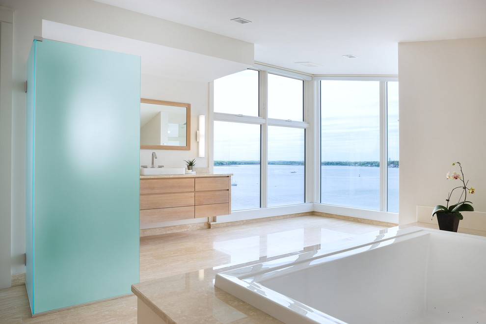 Modern inredning av ett en-suite badrum, med släta luckor, skåp i ljust trä, marmorbänkskiva, ett platsbyggt badkar, beige kakel, porslinskakel, vita väggar, klinkergolv i porslin och ett fristående handfat