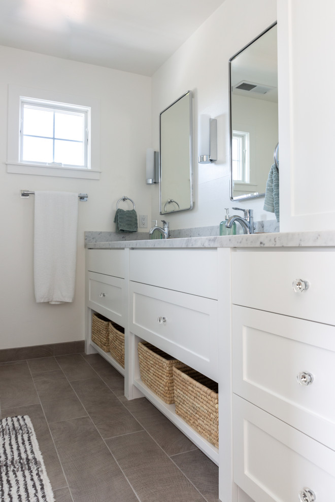 Mid-sized beach style master subway tile and white tile ceramic tile and gray floor alcove shower photo in San Francisco with shaker cabinets, white cabinets, a wall-mount toilet, white walls, an undermount sink, marble countertops, gray countertops and a hinged shower door