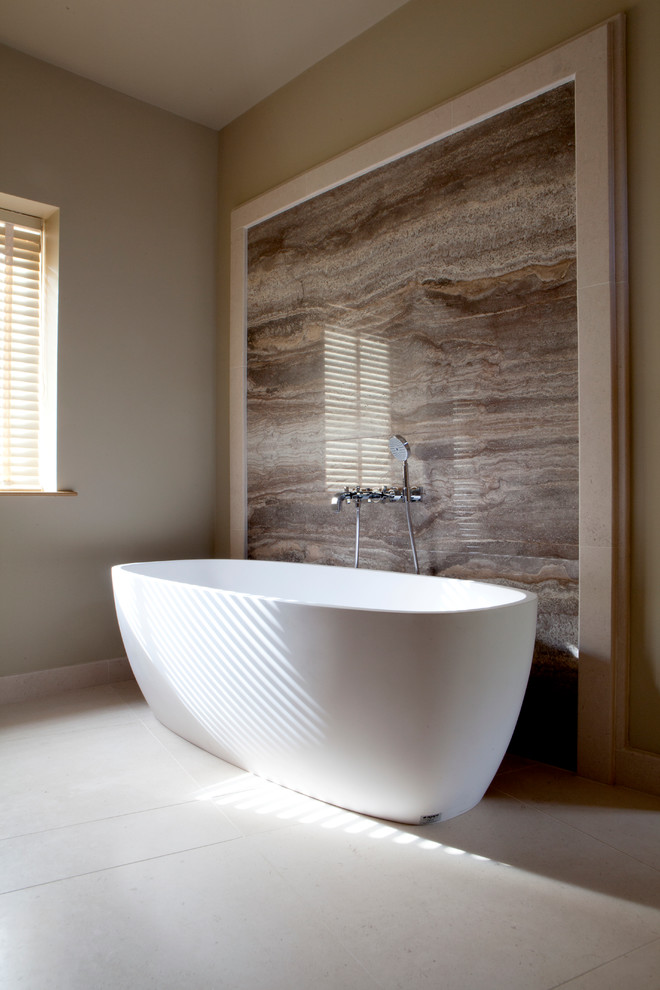 Inspiration för ett funkis badrum, med ett fristående badkar, brun kakel, stenhäll, beige väggar och kalkstensgolv