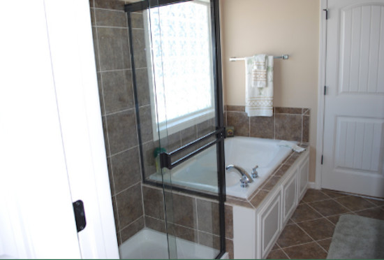 Modelo de cuarto de baño principal clásico de tamaño medio con puertas de armario de madera oscura, encimera de azulejos, jacuzzi, ducha esquinera, baldosas y/o azulejos beige y paredes beige