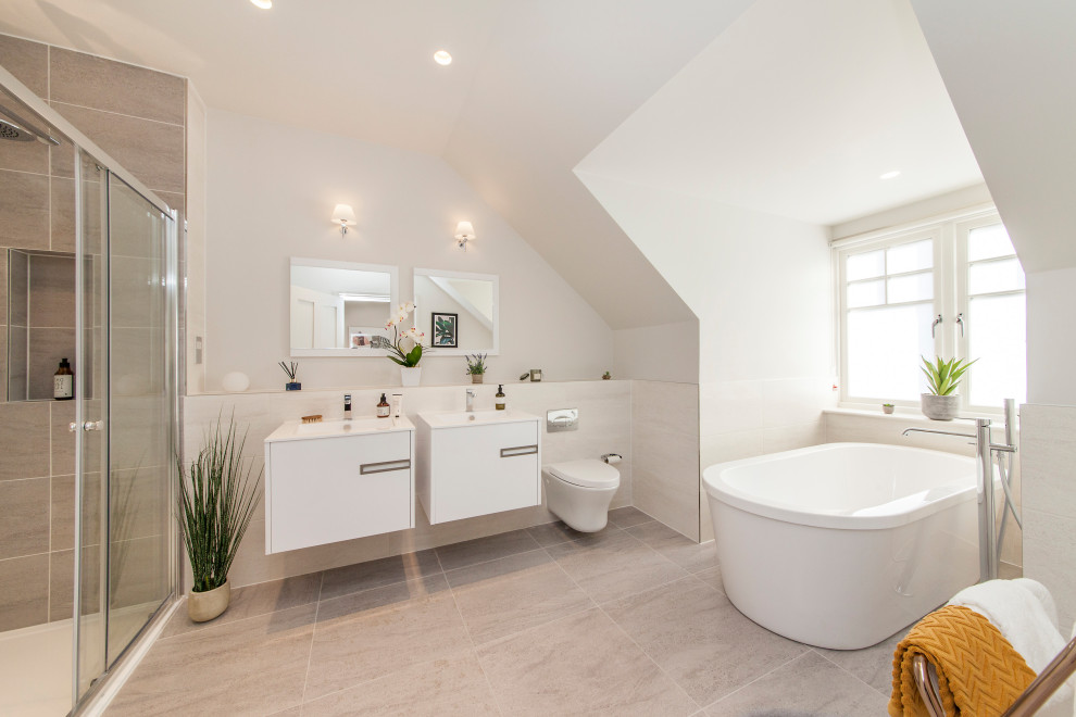 Foto på ett funkis badrum, med släta luckor, vita skåp, ett fristående badkar, grå kakel, vita väggar, ett konsol handfat och grått golv