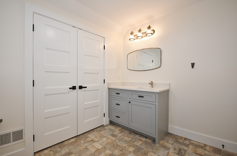 Idées déco pour une salle de bain classique de taille moyenne avec un placard avec porte à panneau encastré, des portes de placard grises, WC séparés, un mur vert, un sol en brique, un lavabo encastré, un plan de toilette en quartz, un sol beige et un plan de toilette blanc.