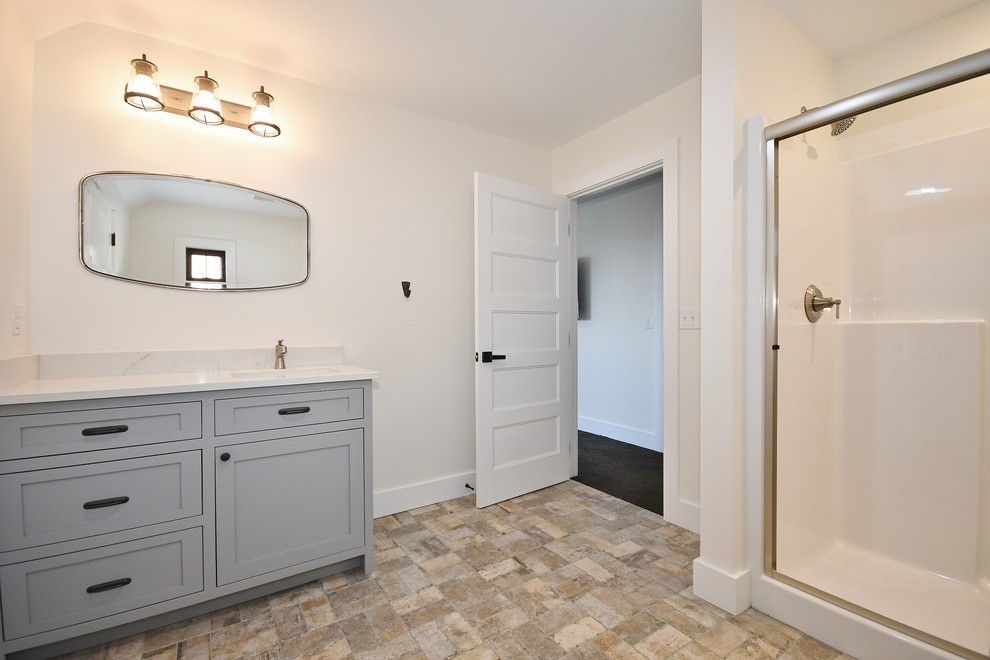 Klassisk inredning av ett mellanstort vit vitt badrum, med luckor med infälld panel, grå skåp, en dusch i en alkov, en toalettstol med separat cisternkåpa, gröna väggar, tegelgolv, ett undermonterad handfat, bänkskiva i kvartsit, beiget golv och dusch med skjutdörr