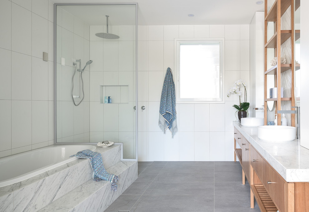 Modernes Badezimmer mit hellbraunen Holzschränken, Einbaubadewanne, weißen Fliesen, Aufsatzwaschbecken, grauem Boden, weißer Waschtischplatte und flächenbündigen Schrankfronten in Brisbane