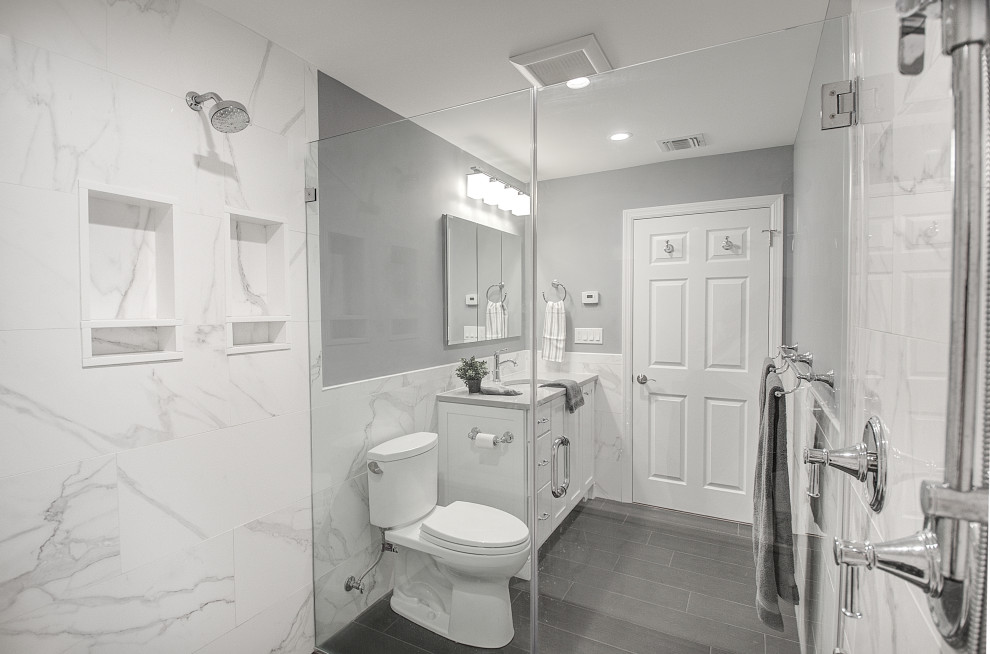 Bathroom - mid-sized transitional white tile and porcelain tile porcelain tile, gray floor and single-sink bathroom idea in Other with recessed-panel cabinets, white cabinets, a two-piece toilet, gray walls, an undermount sink, quartz countertops, a hinged shower door, gray countertops and a built-in vanity