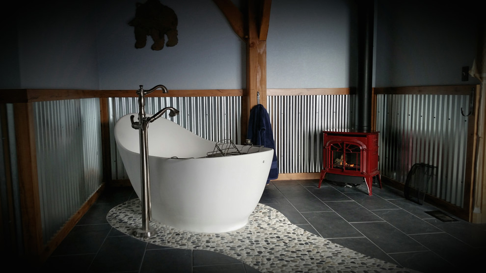 Réalisation d'une grande salle de bain principale chalet avec une baignoire indépendante, un carrelage beige, un carrelage gris, une plaque de galets, un mur gris, un sol en galet et un sol gris.