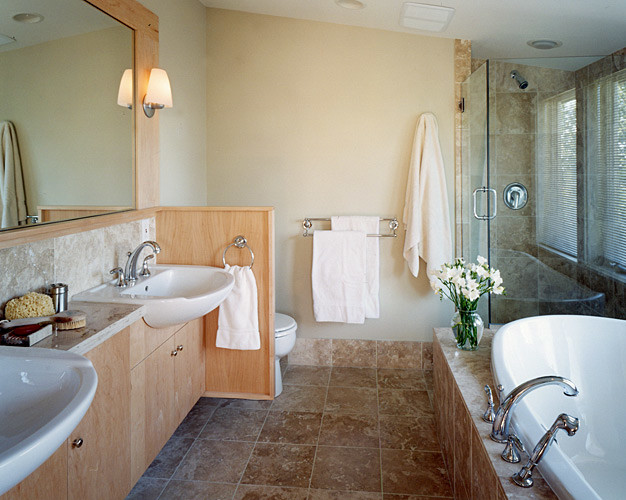 Cette image montre une salle de bain principale craftsman en bois clair de taille moyenne avec une vasque, un placard à porte plane, un plan de toilette en marbre, une baignoire posée, une douche d'angle, WC à poser, un carrelage marron, un carrelage de pierre, un mur beige et un sol en travertin.