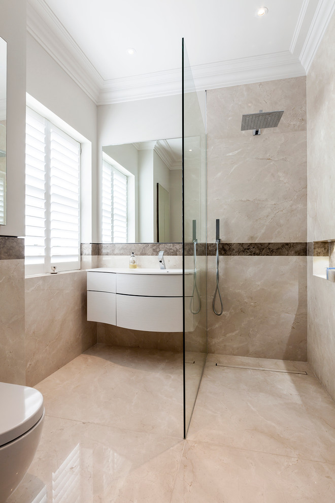 This is an example of a medium sized contemporary family bathroom in London with a walk-in shower, a wall mounted toilet, multi-coloured tiles, porcelain tiles, multi-coloured walls, porcelain flooring, an integrated sink, solid surface worktops, beige floors, an open shower and white worktops.