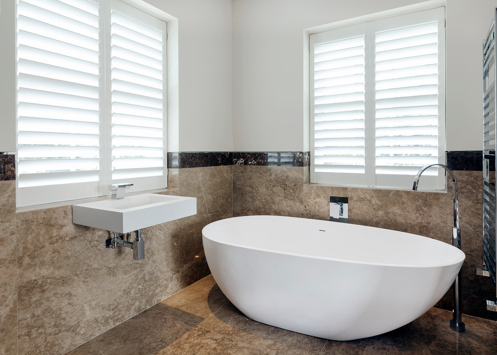 Example of a mid-sized trendy master porcelain tile and brown floor freestanding bathtub design in London with multicolored walls and a wall-mount sink