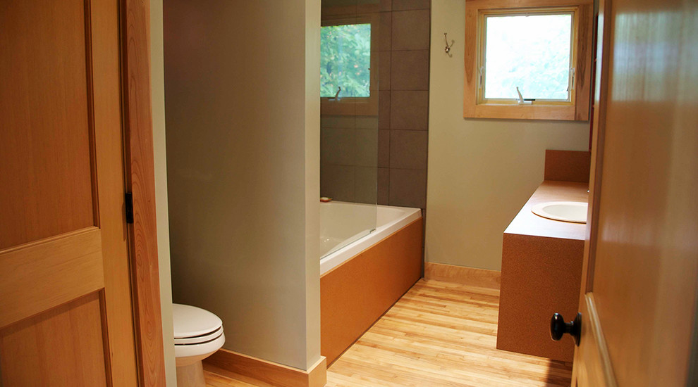 На фото: ванная комната в стиле модернизм с ванной в нише, душем над ванной, светлым паркетным полом и накладной раковиной