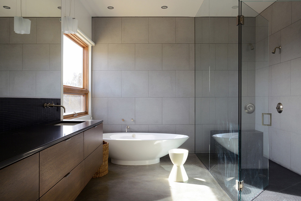 Mid-sized minimalist master gray tile and ceramic tile concrete floor and gray floor bathroom photo in Albuquerque with flat-panel cabinets, dark wood cabinets, a one-piece toilet, white walls, an undermount sink, granite countertops and a hinged shower door