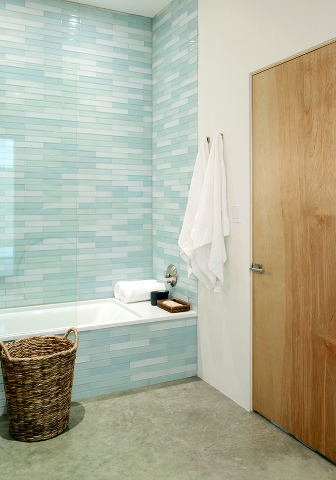 Cette photo montre une salle de bain moderne en bois foncé de taille moyenne avec un placard à porte plane, une baignoire encastrée, un combiné douche/baignoire, WC à poser, un carrelage bleu, un carrelage en pâte de verre, un mur blanc, sol en béton ciré, un lavabo encastré, un plan de toilette en quartz modifié et un sol gris.